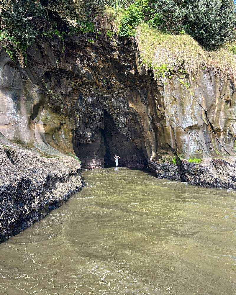 junge Frau kommt aus einer Höhle am Meer