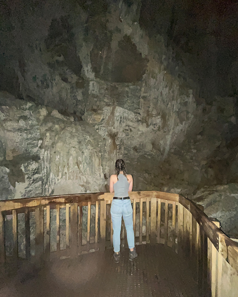 junge Frau von hinten, die auf einer Plattform in einer Höhle steht