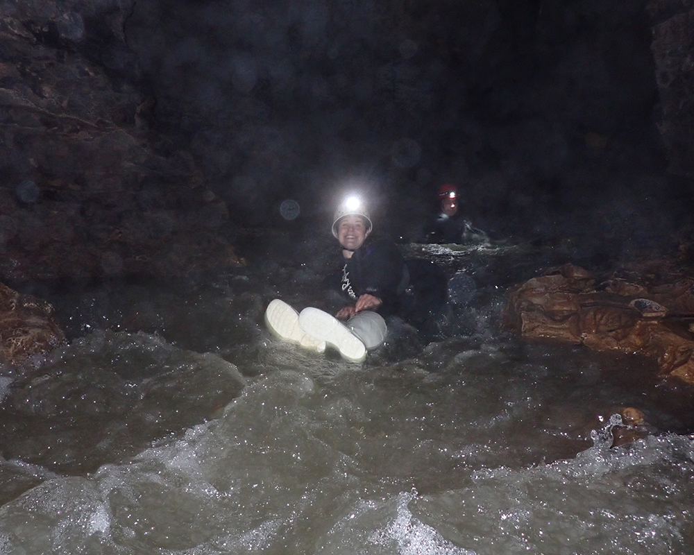 junge Frau sitzt auf einem Reifen und schwimmt durch einen Fluss in einer Höhle