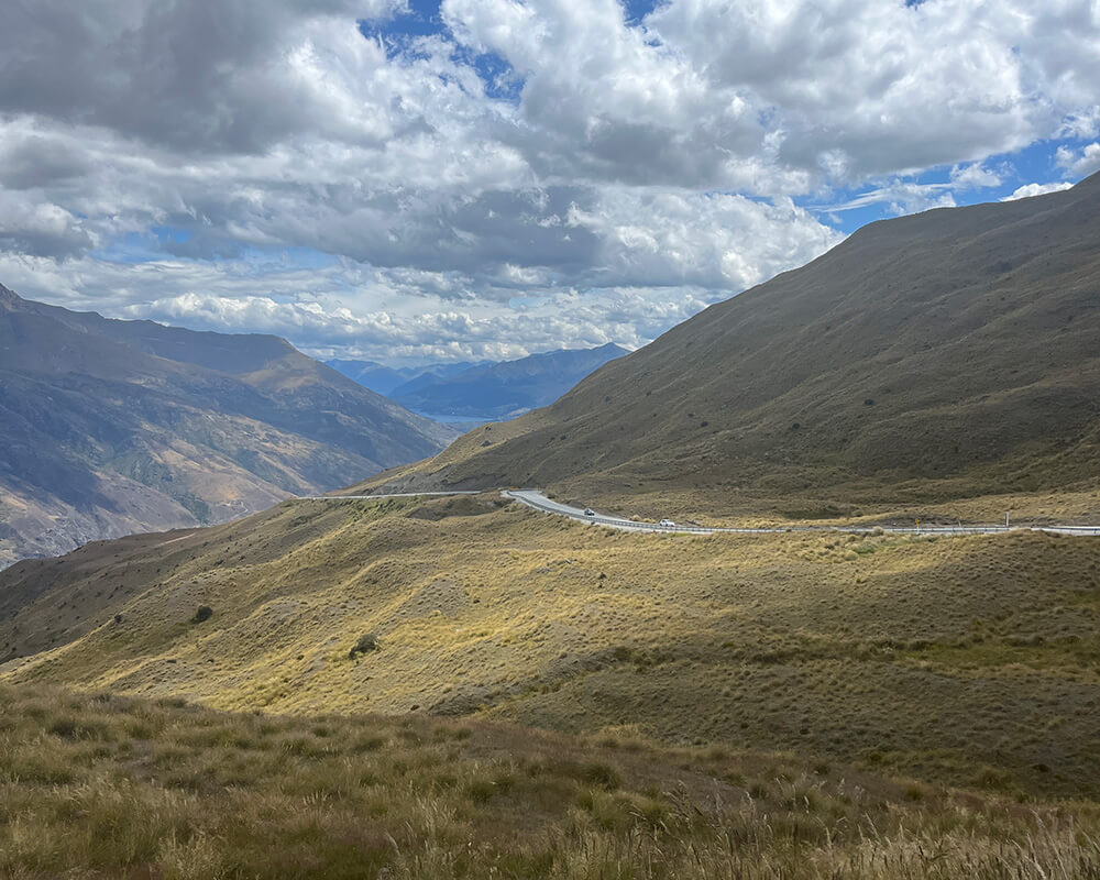 Straße nach Queenstown durch hügeliges, gelbes Grasland